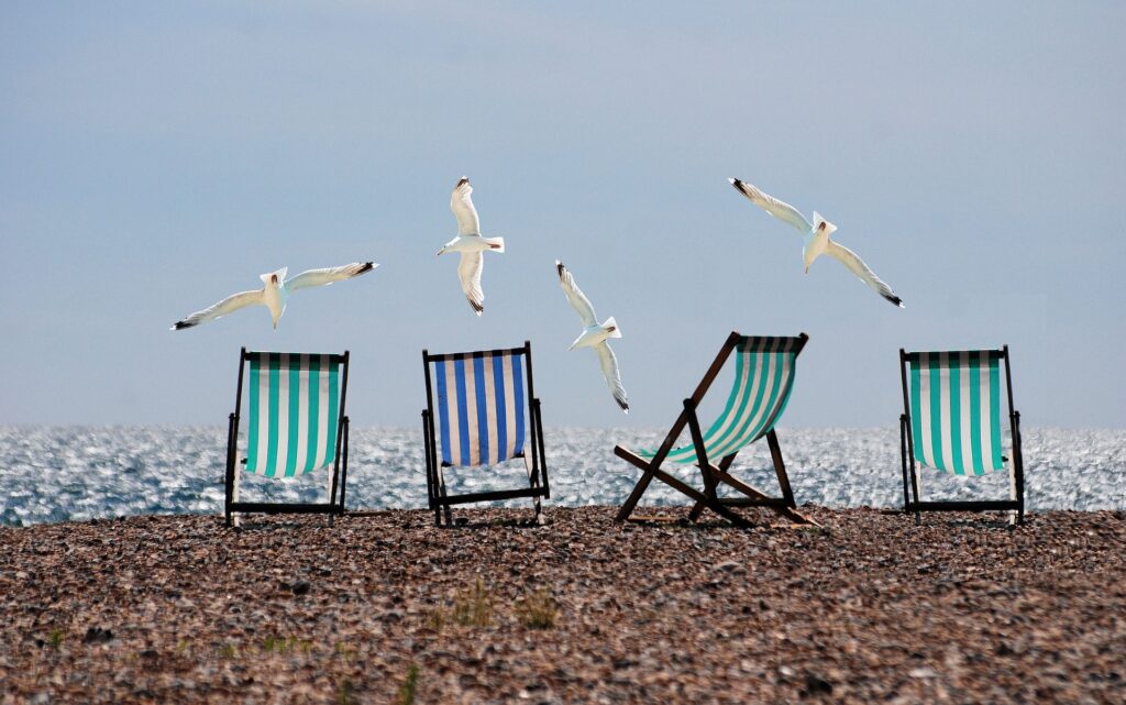Liegestühle auf Strand mit fliegenden Möwen